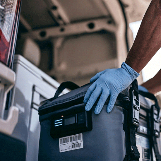 Professional Oasis phlebotomist carrying a sterile specimen transport cooler and clipboard entering a modern healthcare facility