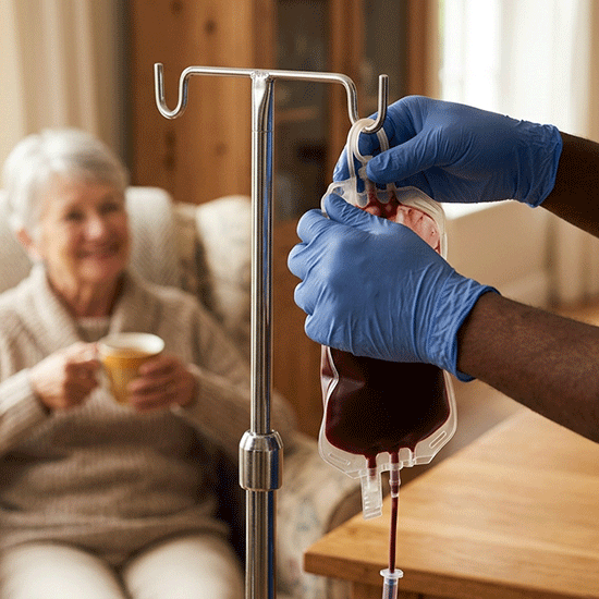 Professional, uniformed phlebotomist performing a gentle blood pressure check for a relaxed patient in a home recliner